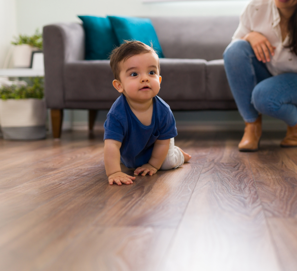 Toddler crawling on a wood floor during a home visit